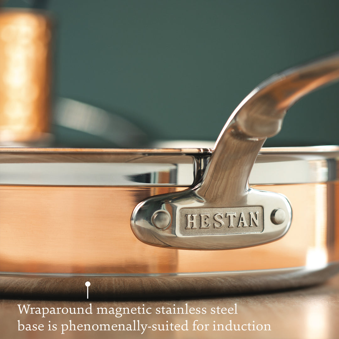 Close-up of a Hestan CopperBond 10-Piece Set pan handle, engraved with the brand name and part of the copper cookware, highlighting its 5-ply construction and induction-compatible magnetic base.