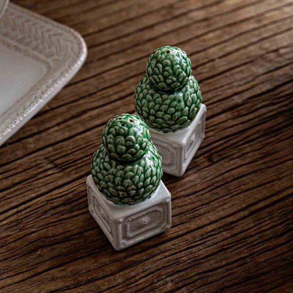 The Juliska Berry & Thread Topiary Salt and Pepper Set features green pinecone-shaped ceramic shakers on white bases—an elegant touch inspired by formal gardens for your table.