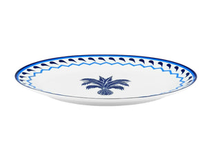 A white porcelain plate featuring a blue patterned rim and central blue palm tree, reminiscent of the Jaipur Blue Oval Platter by Aquazzura Casa.