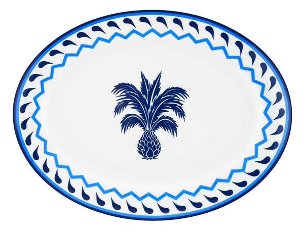 The Aquazzura Jaipur Blue Oval Platter by Aquazzura Casa is a white porcelain piece showcasing a blue palm tree design in the center, complemented by a blue patterned border around the edge and featuring exquisite handcrafted details.