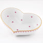 The Herend Heart Bowl is a white, heart-shaped ceramic dish with a gold rim and small pink hearts, featuring hand-painted designs for an artistic touch.