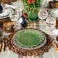 The Juliska Rustic Ring Placemat, paired with green patterned plates, glassware, bamboo-handled cutlery, a potted plant centerpiece, and a checked tablecloth, creates an inviting and textured table setting that beautifully enhances your rustic decor.