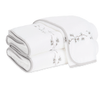 Two folded white towels from the Matouk Jasmine Giza Bath Collection in Cloud, featuring light gray edging and a subtle branch and blossom embroidery, crafted from plush Egyptian cotton terry for a luxurious bathroom experience.