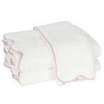 Two white towels with light pink scalloped edges from the Matouk Jasper Bath Collection are stacked against a plain background.