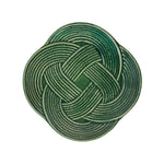 A green, intricately woven knot in a circular, symmetrical pattern on a crisp white background captures the timeless elegance of Juliska's Le Panier Mystic Knot Basil Dinnerware and Serveware Collection.