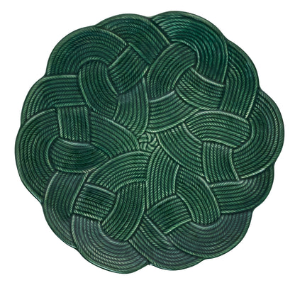A green plate with a braided rope pattern, featuring a circular, interwoven design on white—ideal holiday tableware from Juliska’s Le Panier Mystic Knot Basil Dinnerware and Serveware Collection.