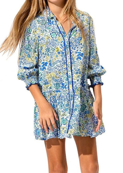 A woman wearing a Poupette St Barth Girls' Tesorino mini dress with long sleeves and a button front. Only the dress and part of her hair are visible.