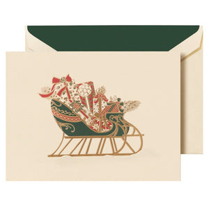 The Crane Sleigh Holiday Card Set features cream cards with a green and gold sleigh filled with gifts and greenery, plus matching envelopes—perfect for sending festive wishes this holiday season.