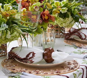 An exquisite table setting featuring a Kim Seybert Cabochon Placemat in Natural & Brown, adorned with floral arrangements, chic glassware, and a decorated plate with a cloth napkin and holder. Perfect for creating luxurious galas that dazzle with subtle elegance.
