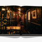 Open book titled "Laperouse: A Parisian Icon Since 1766" by Assouline, showing a dimly lit, ornate hallway lined with framed portraits, patterned wallpaper, and antique fixtures that evoke the ambience of a hidden wine cellar within the legendary Parisian establishment.
