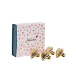 The Juliska Berry & Thread Heart Napkin Ring and Place Card Holder Collection features four gold-tone, hammered heart napkin rings, presented before a white gift box decorated with pink hearts and cursive script.