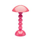The Addison Ross Bobbin LED Cordless Lamp features a modern pink dome-shaped shade and stacked bobbin-style base, offers adjustable light levels, and is shown against a plain white background.