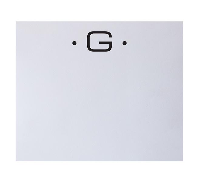 The Black Ink Black Initial Large Notepad features a bold black "G" centered near the top of a white page, accented by a dot on each side—an elegant addition to fine stationery crafted from high-quality paper.