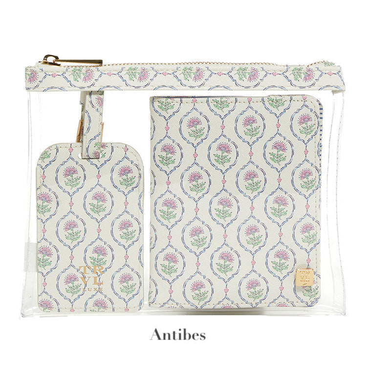 A transparent pouch holds the LUXE Saffiano Travel Set by TRVL Design—a matching floral-patterned luggage tag and passport cover, labeled "Antibes" below.