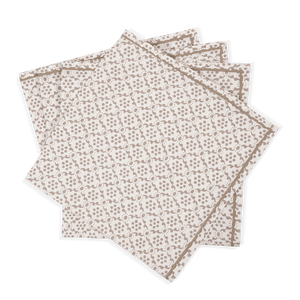 The Laksha Napkin Set by Matouk features four beige cloth napkins adorned with a delicate brown geometric pattern, reminiscent of block printing, artfully fanned out against a plain white background.