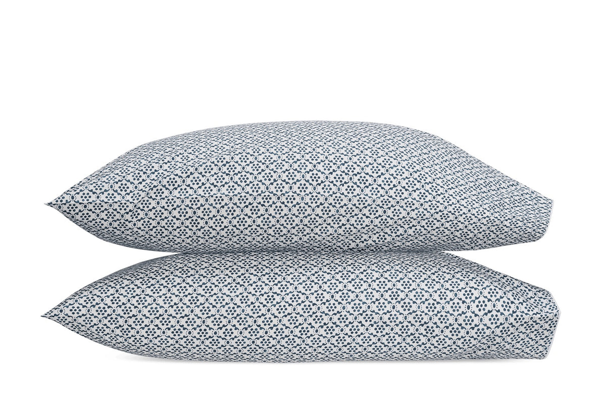 Two rectangular pillows from the Laksha Bedding Collection by Matouk, featuring a blue and white geometric diamond pattern inspired by Indian block printing, stacked on top of each other against a white background.
