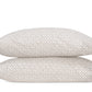 Two white pillows from the Matouk Laksha Bedding Collection, featuring a beige geometric pattern inspired by Indian block printing, are stacked one atop the other against a plain white background.
