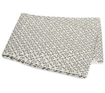 The Laksha Bedding Collection by Matouk features folded white fabric adorned with an olive green polka dot pattern inspired by Indian block printing, displayed on a plain white background.