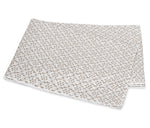 A folded white blanket from the Laksha Bedding Collection by Matouk, featuring a beige dot and line pattern inspired by Indian block printing techniques, displayed on a plain white background.