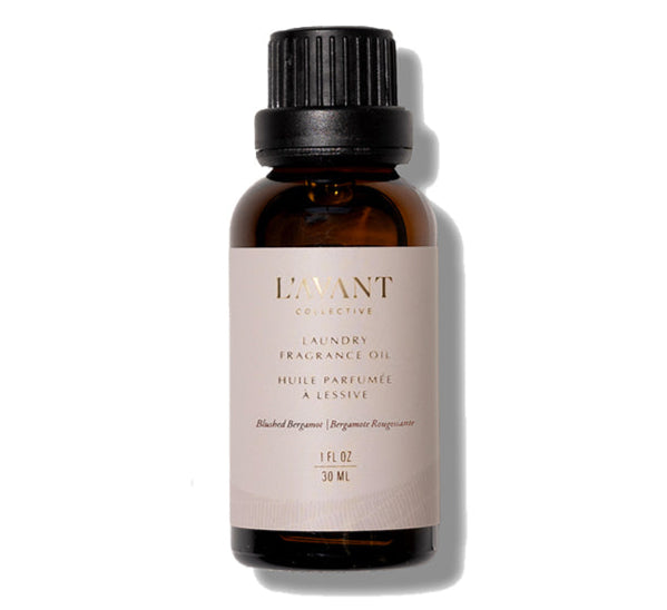 A 30 ml amber glass bottle of L'Avant Collective Laundry Oil, Blushed Bergamot, with a black screw cap and beige label—perfect for adding a subtle bergamot fragrance to dryer balls or your laundry routine.