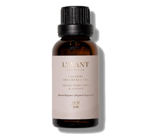 A brown glass bottle of L'Avant Laundry Oil, Blushed Bergamot by L'Avant Collective, labeled with product details, ideal for use with dryer balls to elevate your laundry experience.