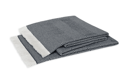 The Leo Throw by Matouk is an oversized black-and-white herringbone blanket with white fringed edges, made from 100% cotton for comfort and style, shown folded on a plain background.
