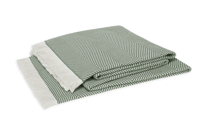 The Matouk Leo Throw, featuring an oversized green and white herringbone pattern with white fringe on one end, is displayed against a white background.