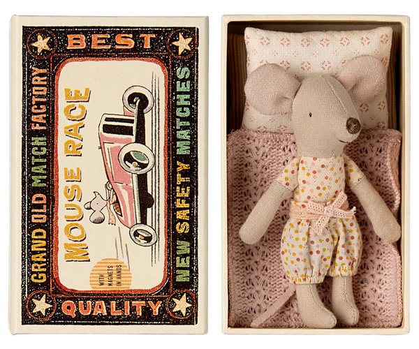 A Maileg Little Sister mouse, dressed in a charming polka-dot outfit, rests comfortably in a matchbox bed crafted from soft fabrics, nestled inside a cardboard box. The box is labeled "Maileg Little Sister, Mouse in Matchbox" and features delightful vintage matchbox-style graphics on the lid.