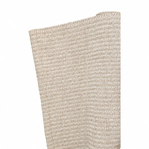 A close-up of the Lina Strie Rug by Magdalena York, a beige woven indoor-outdoor rug, partially rolled up against a white background.