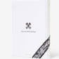 Assouline’s “Londolozi: The Safari that Changed Everything” is a white hardcover book featuring a black emblem, the phrase “Protector of All Living Things,” and a tree bark pattern evoking wilderness, conservation, and community development.