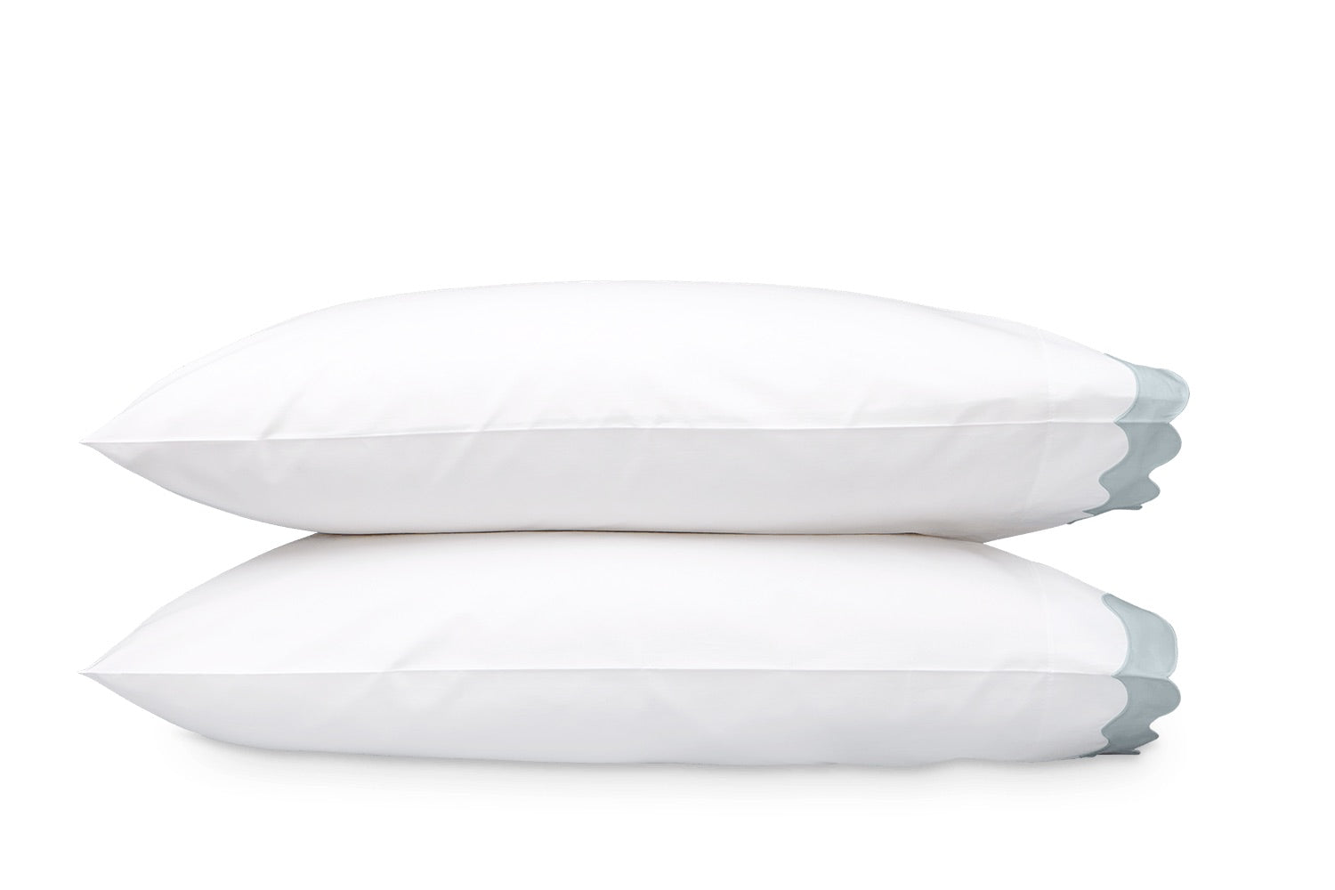 Two white pillows from the Lorelei Bedding Collection by Matouk are stacked on top of each other, crafted from luxurious 600 thread count Egyptian cotton, with a subtle blue accent visible on the right edge of each pillow.