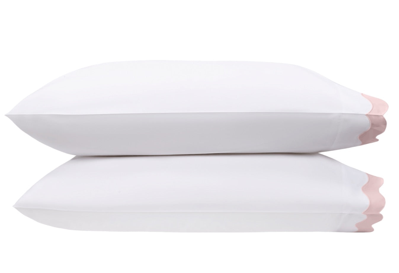 Two pillows from the Lorelei Bedding Collection by Matouk, made of luxurious white Egyptian cotton with a 600 thread count and finished with delicate light pink appliqué scallop edges, are stacked on top of each other against a plain white background.