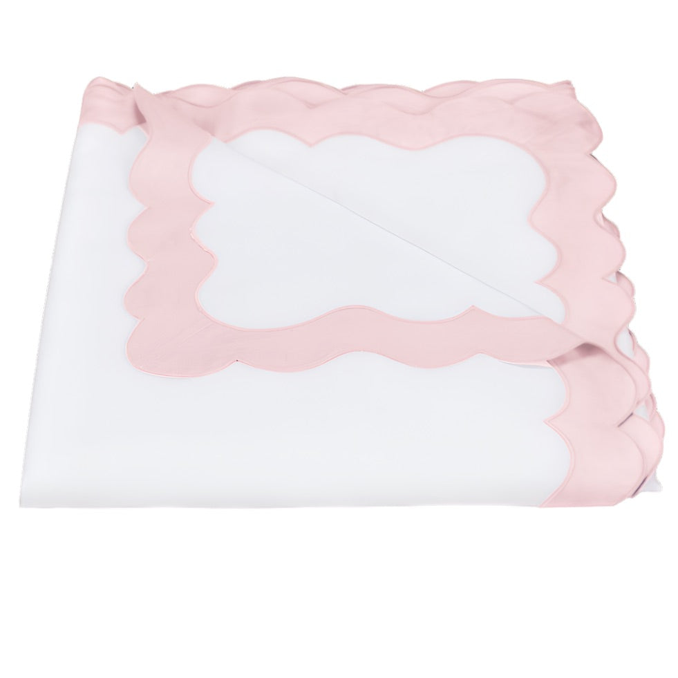 A folded white sheet from the Lorelei Bedding Collection by Matouk, crafted from luxurious Egyptian cotton with pale pink appliqué scallop borders and a 600 thread count, beautifully arranged with one corner turned down to showcase the exquisite edge detailing.
