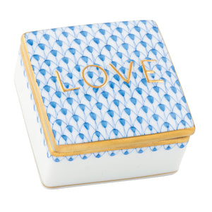The Herend Love Box is a square porcelain box featuring hand-painted blue patterns, gold trim, and "LOVE" in gold letters—an elegant touch of luxury home decor.