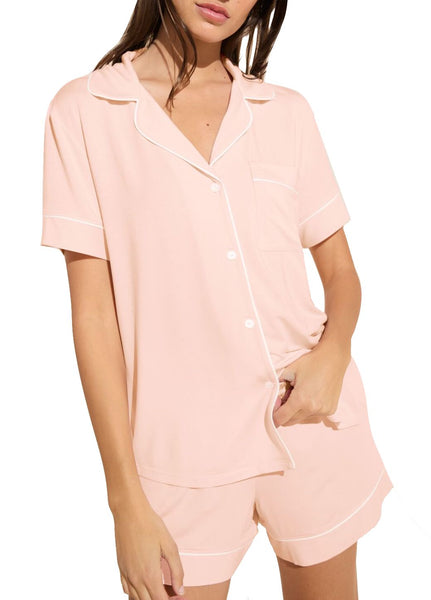 Woman wearing a pink short-sleeved Eberjey Gisele Relaxed Short PJ Set with white piping, standing against a neutral background.