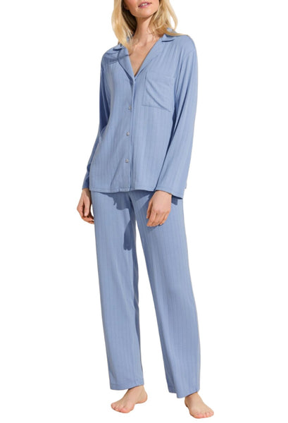 A woman standing in a light blue striped Eberjey Gisele Rib Long PJ Set consisting of a button-up shirt and matching pants.