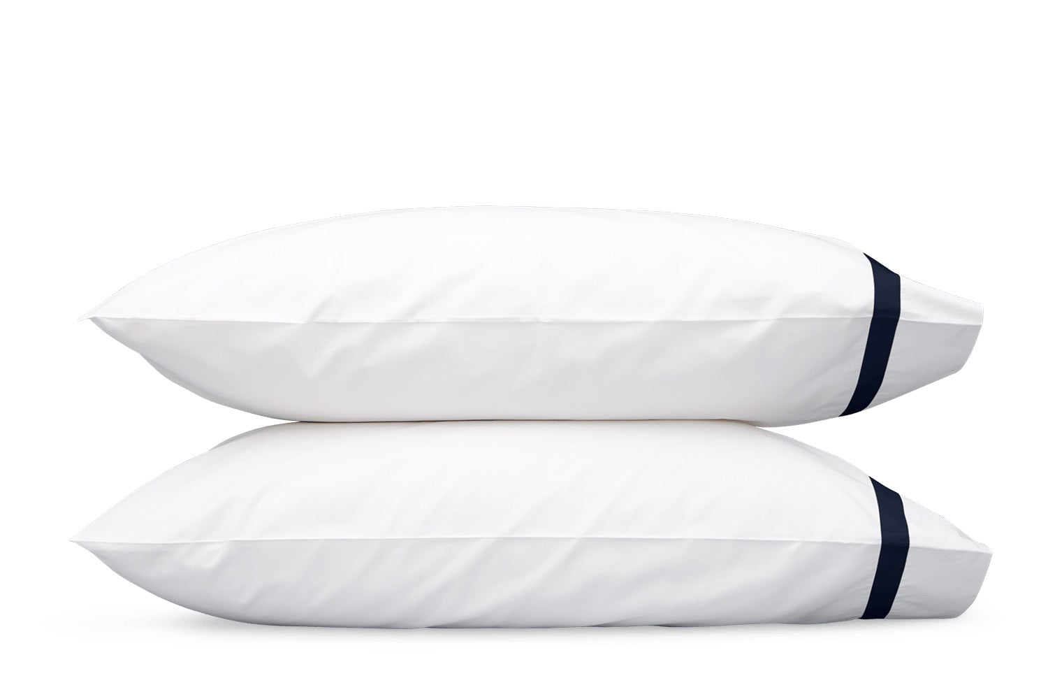 Two white pillows from the Lowell Bedding Collection by Matouk are stacked atop one another, each featuring a dark horizontal stripe near the edge. These luxurious pillows, crafted from Egyptian cotton percale and boasting a smooth 600 thread count finish, elegantly showcase the sophistication of high-end bedding, isolated on a white background.