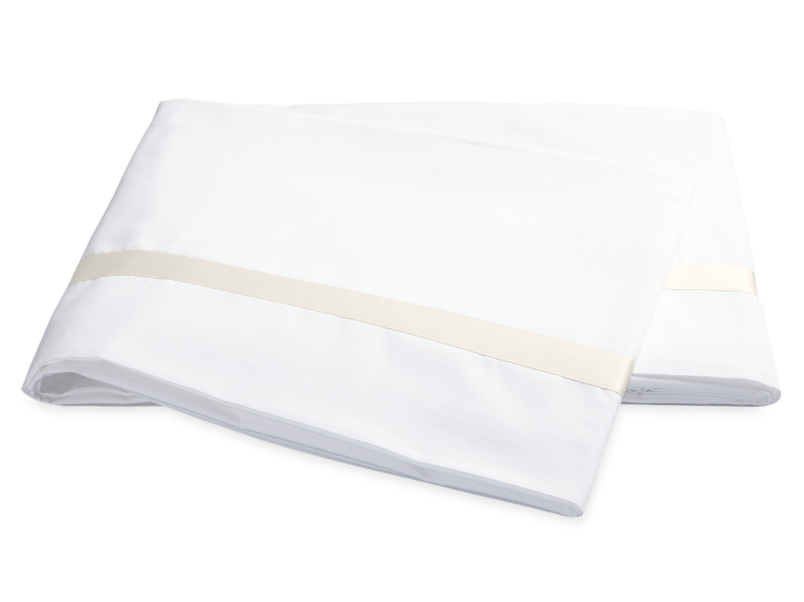 Two folded ivory pillowcases from the Matouk Lowell Bedding Collection, featuring a subtle sateen tape border and crafted from luxurious Egyptian cotton percale, are placed on a plain background.