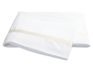 Two folded ivory pillowcases from the Matouk Lowell Bedding Collection, featuring a subtle sateen tape border and crafted from luxurious Egyptian cotton percale, are placed on a plain background.
