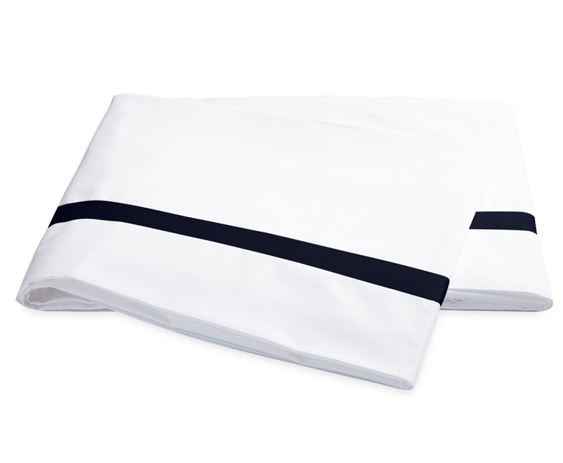 Two neatly folded pillowcases from the Matouk Lowell Bedding Collection, crafted from luxurious 600 thread count Egyptian cotton percale, feature a single horizontal black stripe near the edge and are displayed side by side on a plain white background.