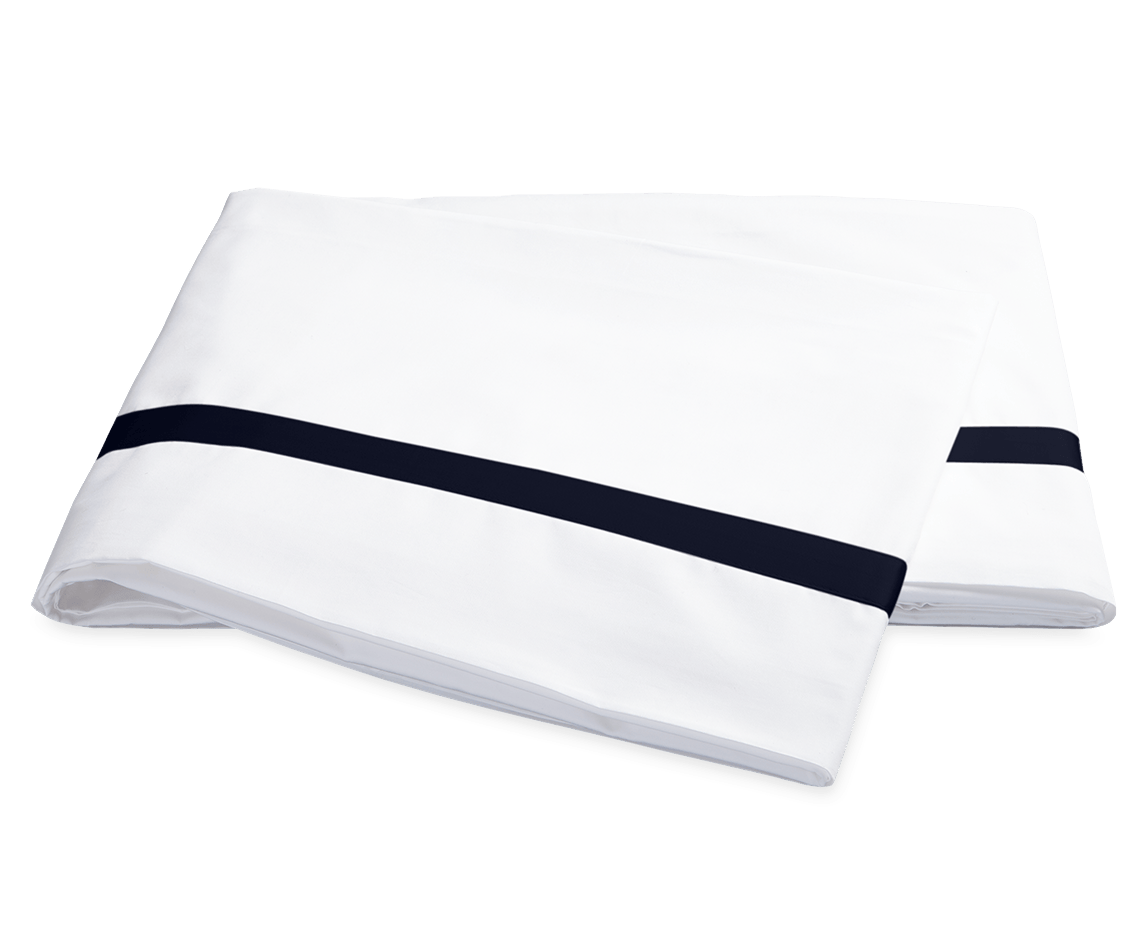 Two folded white pillowcases from the Matouk Lowell Bedding Collection in Navy, crafted from 600 thread count Egyptian cotton percale with a single navy stripe near the edge, are displayed on a plain background.