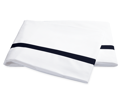 Two folded white pillowcases from the Matouk Lowell Bedding Collection in Navy, crafted from 600 thread count Egyptian cotton percale with a single navy stripe near the edge, are displayed on a plain background.
