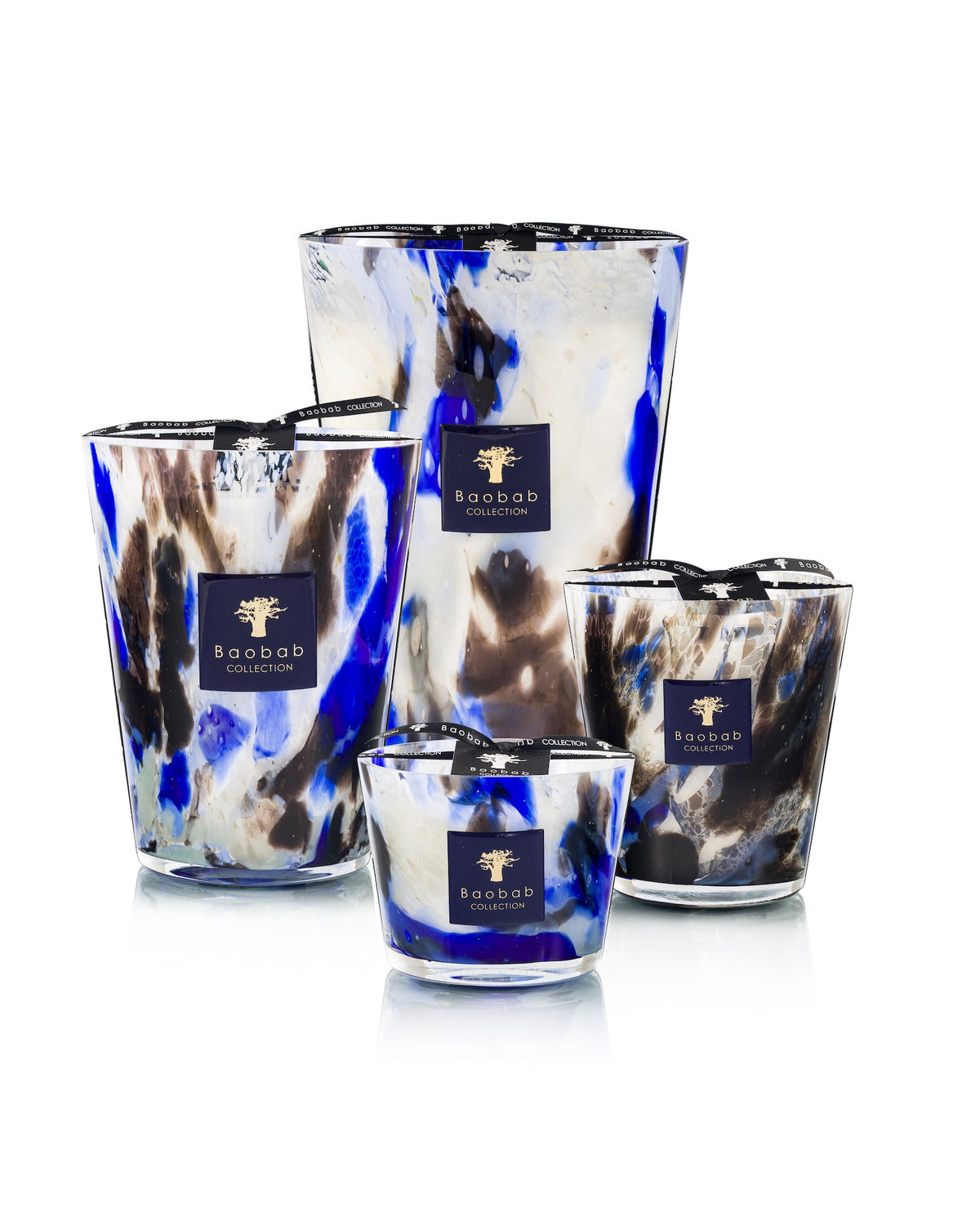 Four hand-blown Baobab Collection Halona Blue World candles of varying sizes, featuring a marbled blue, black, and white design with a navy blue square label on each.