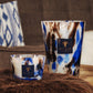 Two Baobab Collection Halona Blue World candles with a blue, white, and brown marbled pattern, each featuring a square logo badge and a cobalt accent.