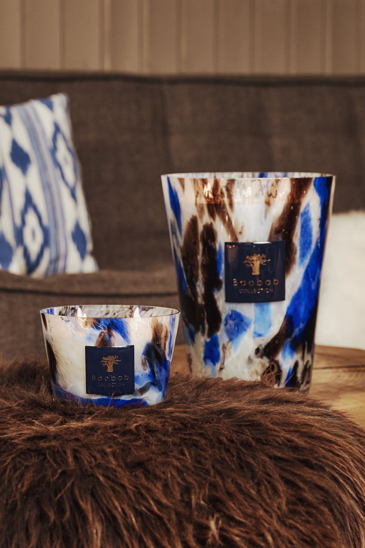 Two Baobab Collection Halona Blue World candles with a blue, white, and brown marbled pattern, each featuring a square logo badge and a cobalt accent.