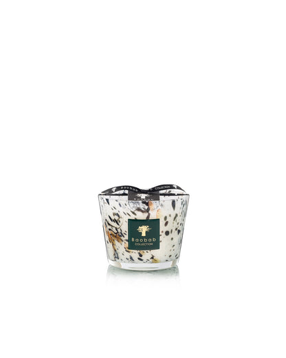 A hand-blown Baobab Collection Halona White World Candle with a black and white speckled pattern, dark green label with gold tree logo, and a black ribbon rim.