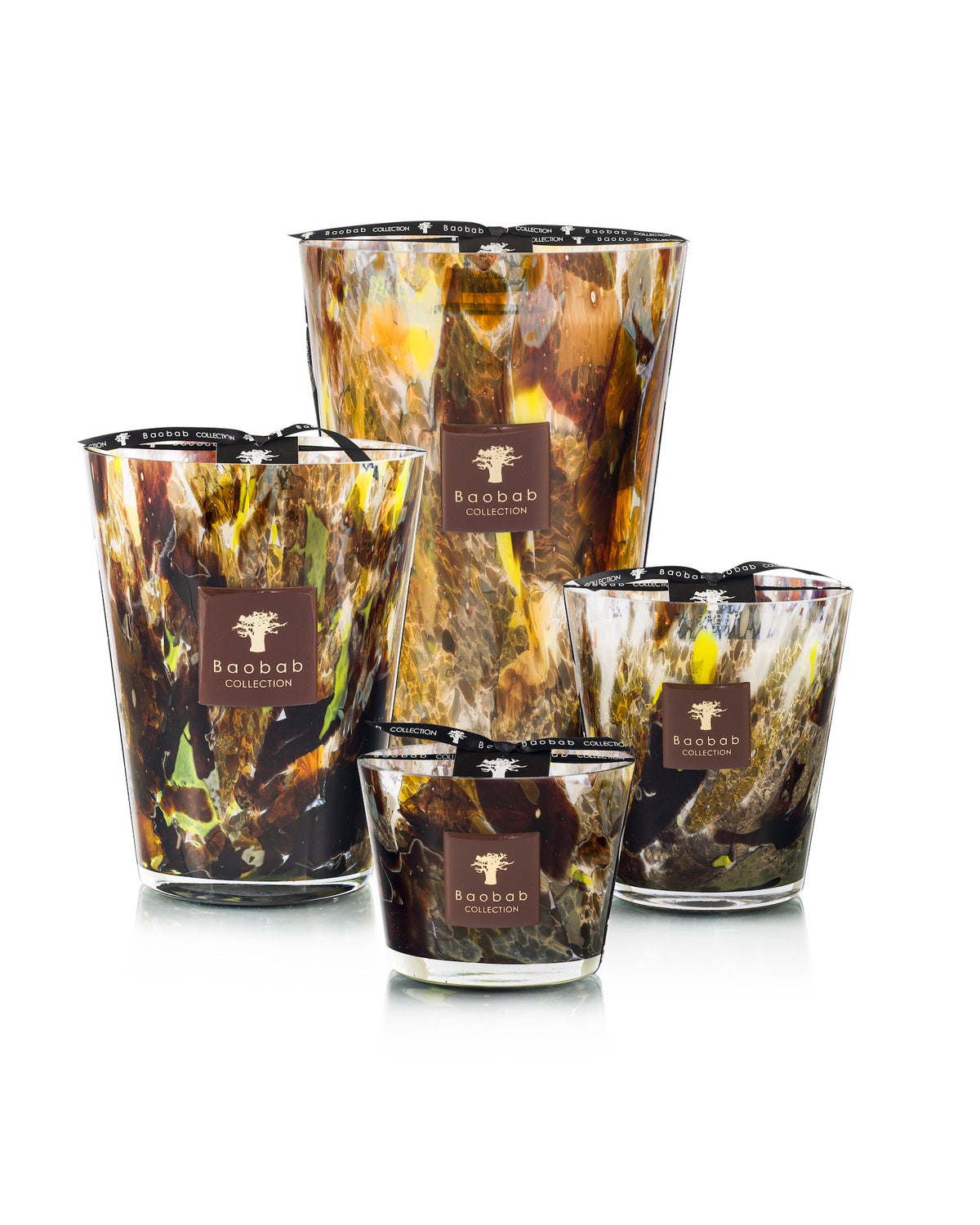 Four Baobab Collection Halona Yellow World Candle hand-blown glass vessels in varying sizes, featuring an abstract brown, yellow, and black swirled pattern with a square label on each.