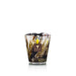 Baobab Collection Halona Yellow World Candle in a hand-blown glass vessel with a multicolored abstract pattern and a square logo patch on the front.
