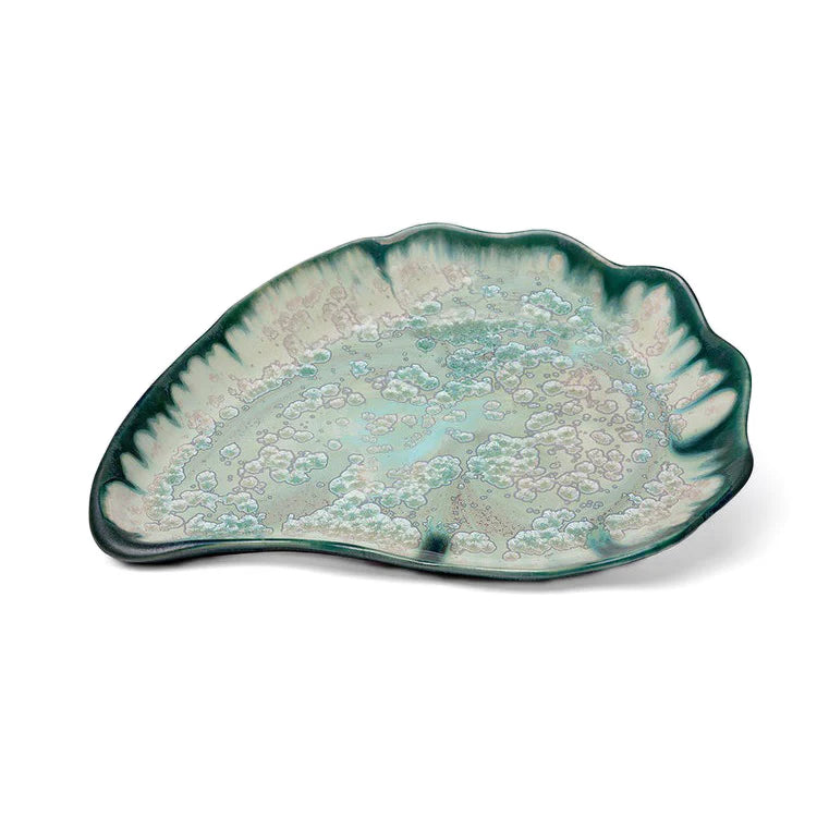 The Large Oyster Plate Collection by AE Ceramics features a ceramic serving platter with an abstract leaf shape, scalloped edges, and a green-blue glazed pattern.