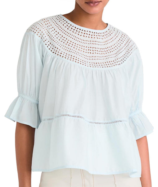 Woman wearing a light blue OEKO-TEX® certified Merlette New York Sol Eyelet Top with lace detailing.